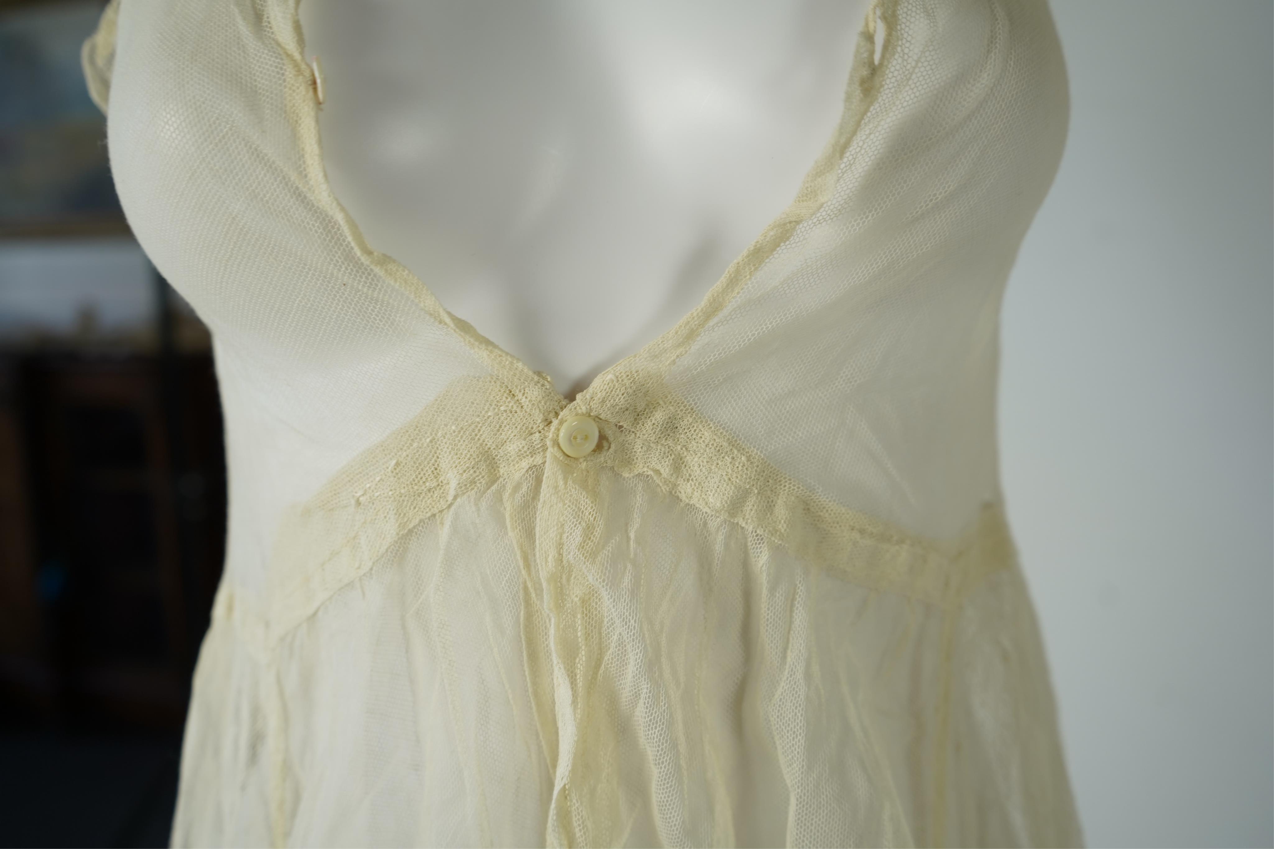 An early 20’s cream net ladies summer dress and net petticoat, designed with a lace inset front skirt, yolk and sleeves.103cm long. Condition - both need re-laundering and some seams tidying.